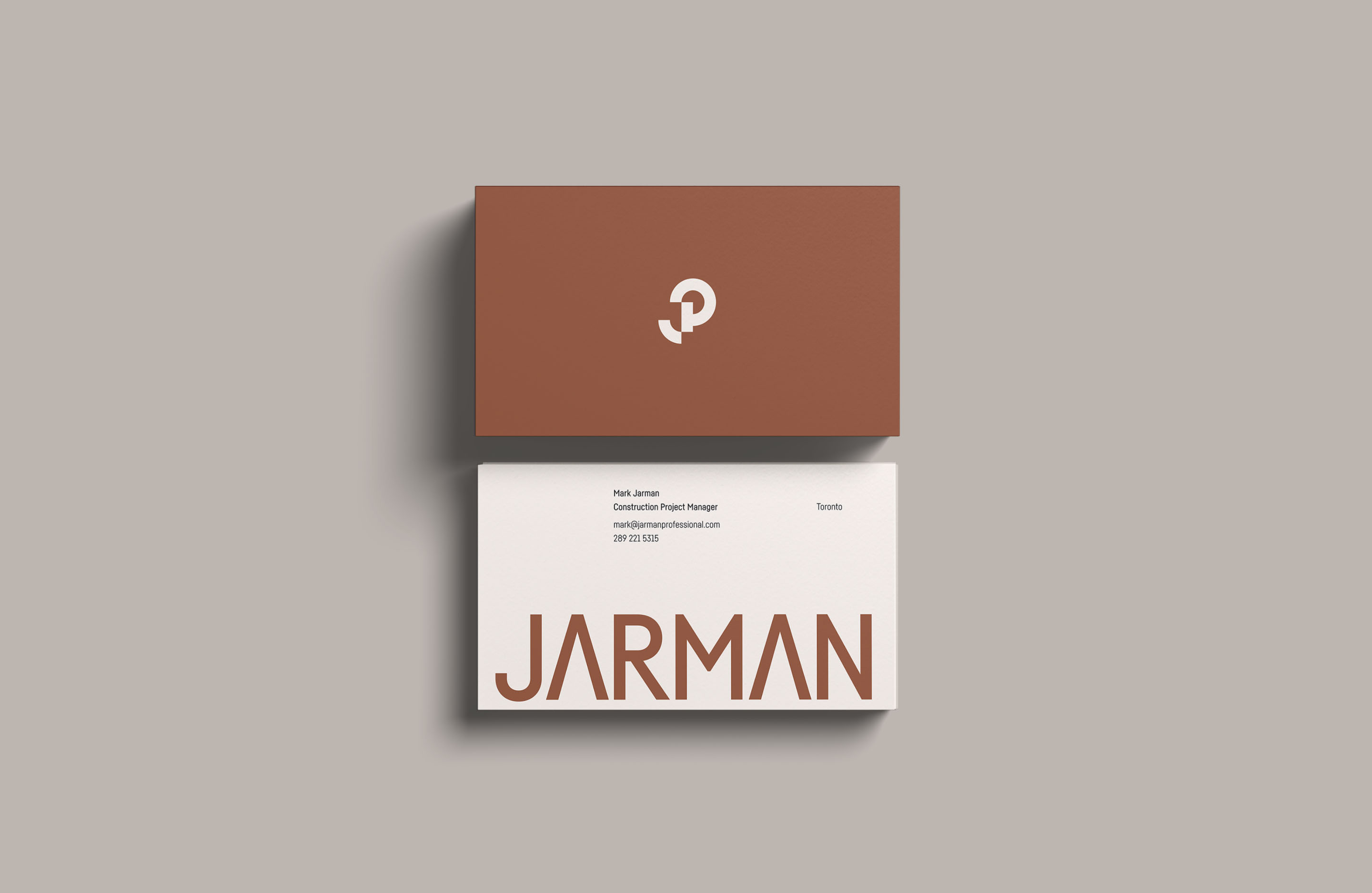 Jarman Professional business cards featuring the wordmark, geometric monogram and brown brand colour.