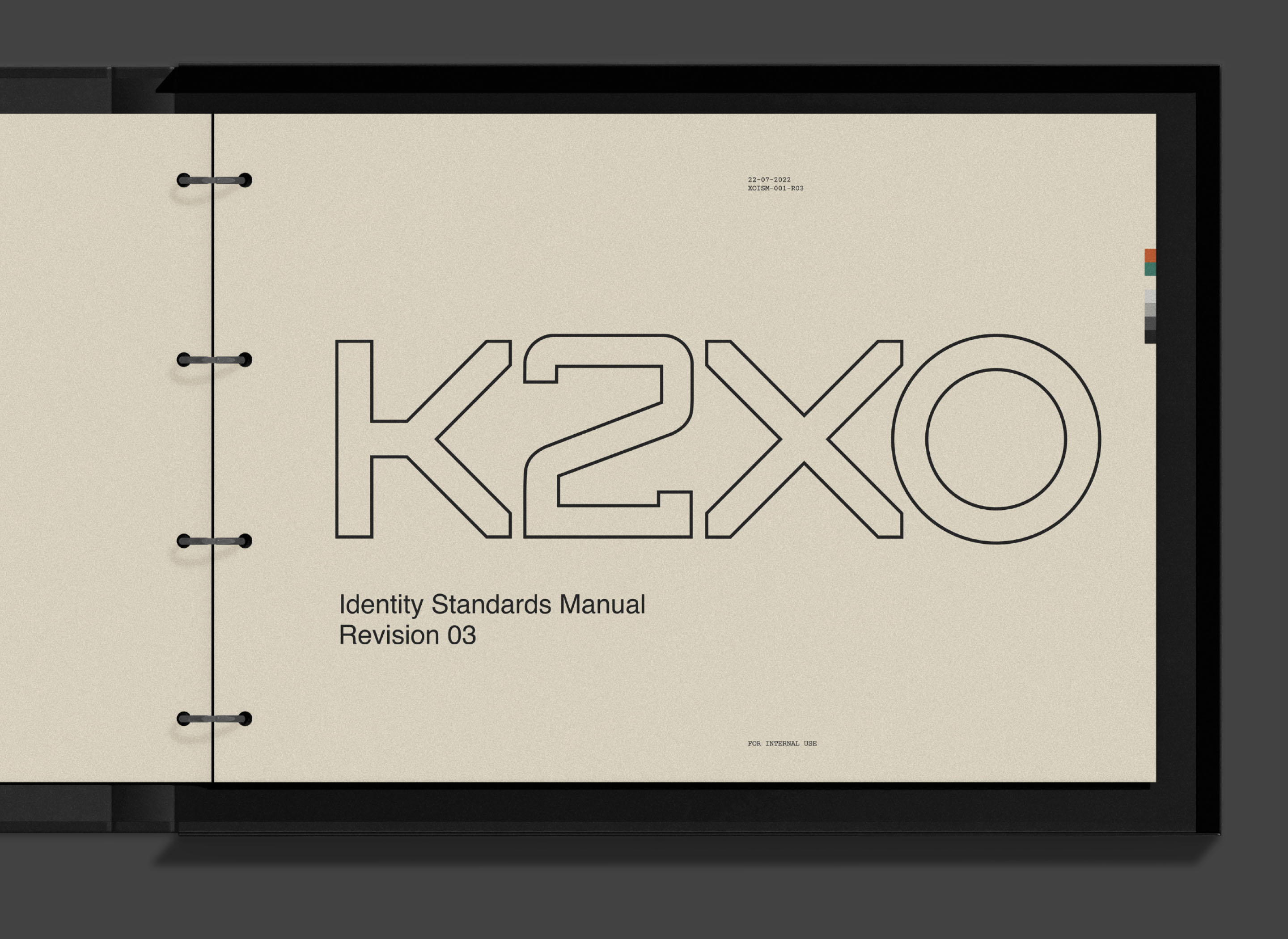 K2XO identity standards manual featuring the custom geometric wordmark on an exposed-ring binder.