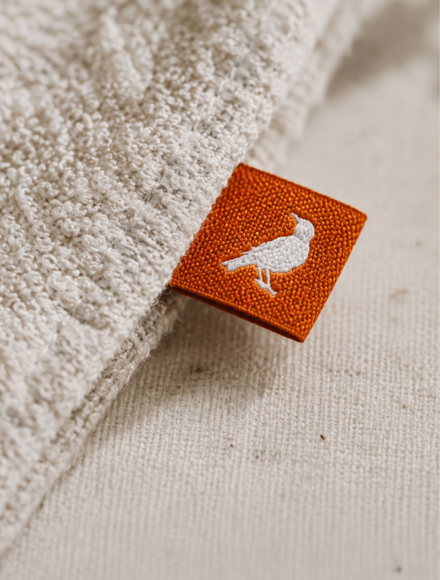 Orange woven clothing label featuring the American robin symbol from the Mike Fuhr identity.